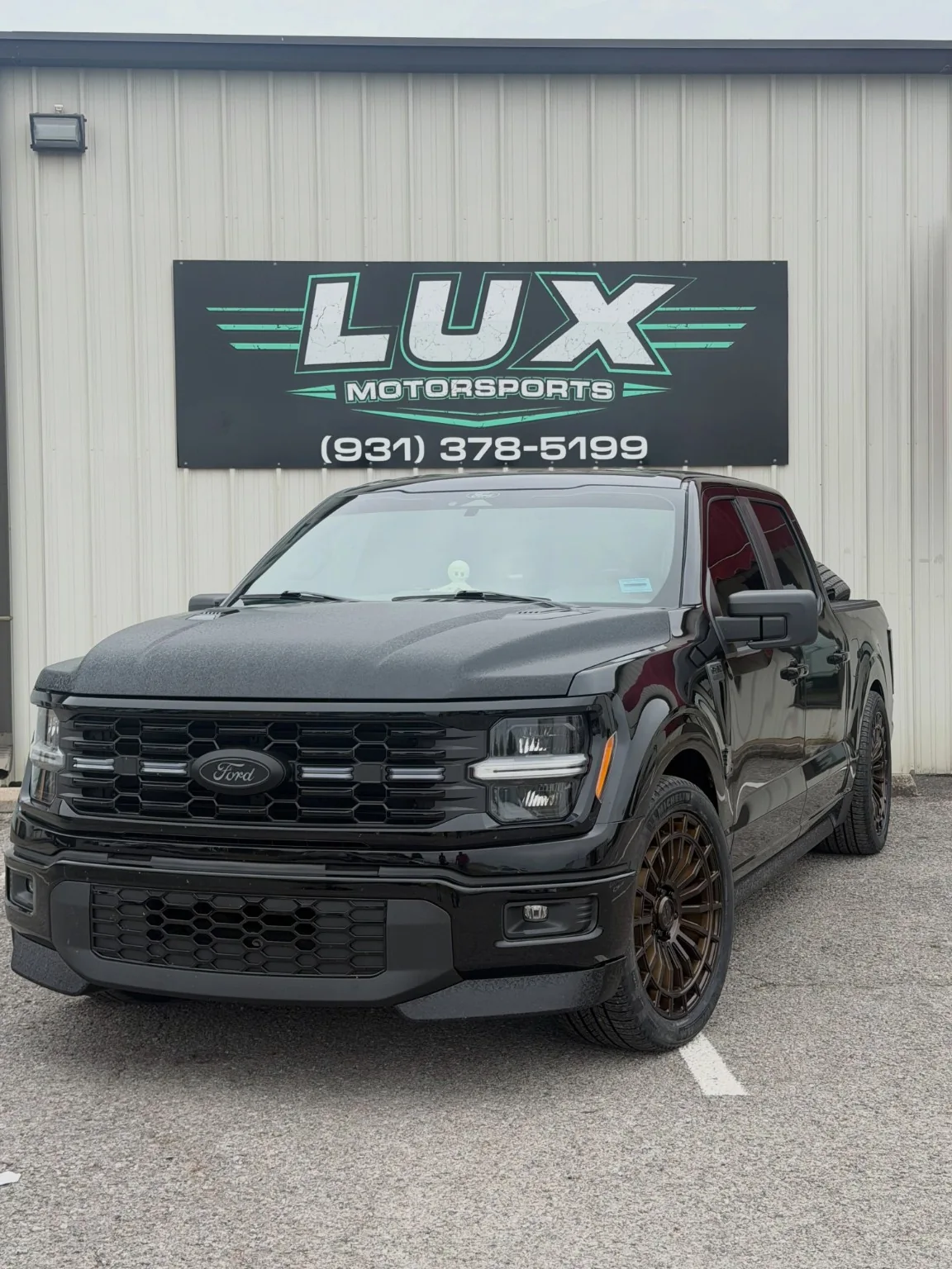 Black Ford pickup photographed outside the LUX sign