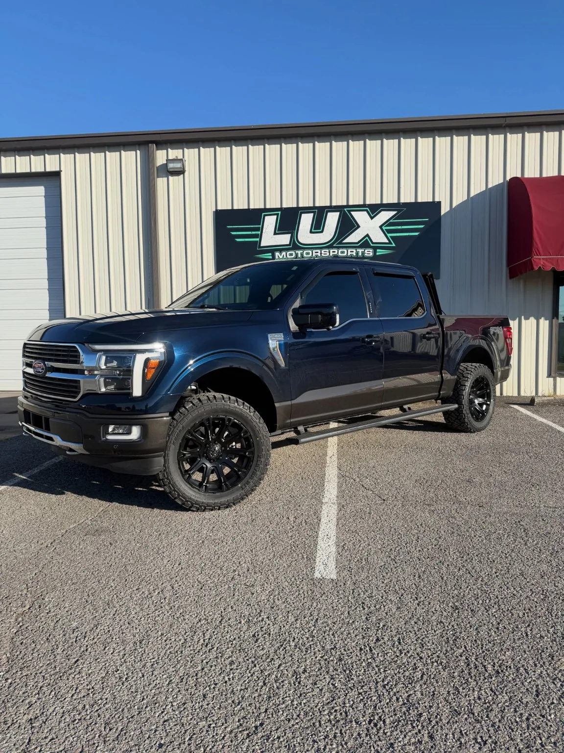 Blue Ford pickup displayed at the LUX Motorsports shop