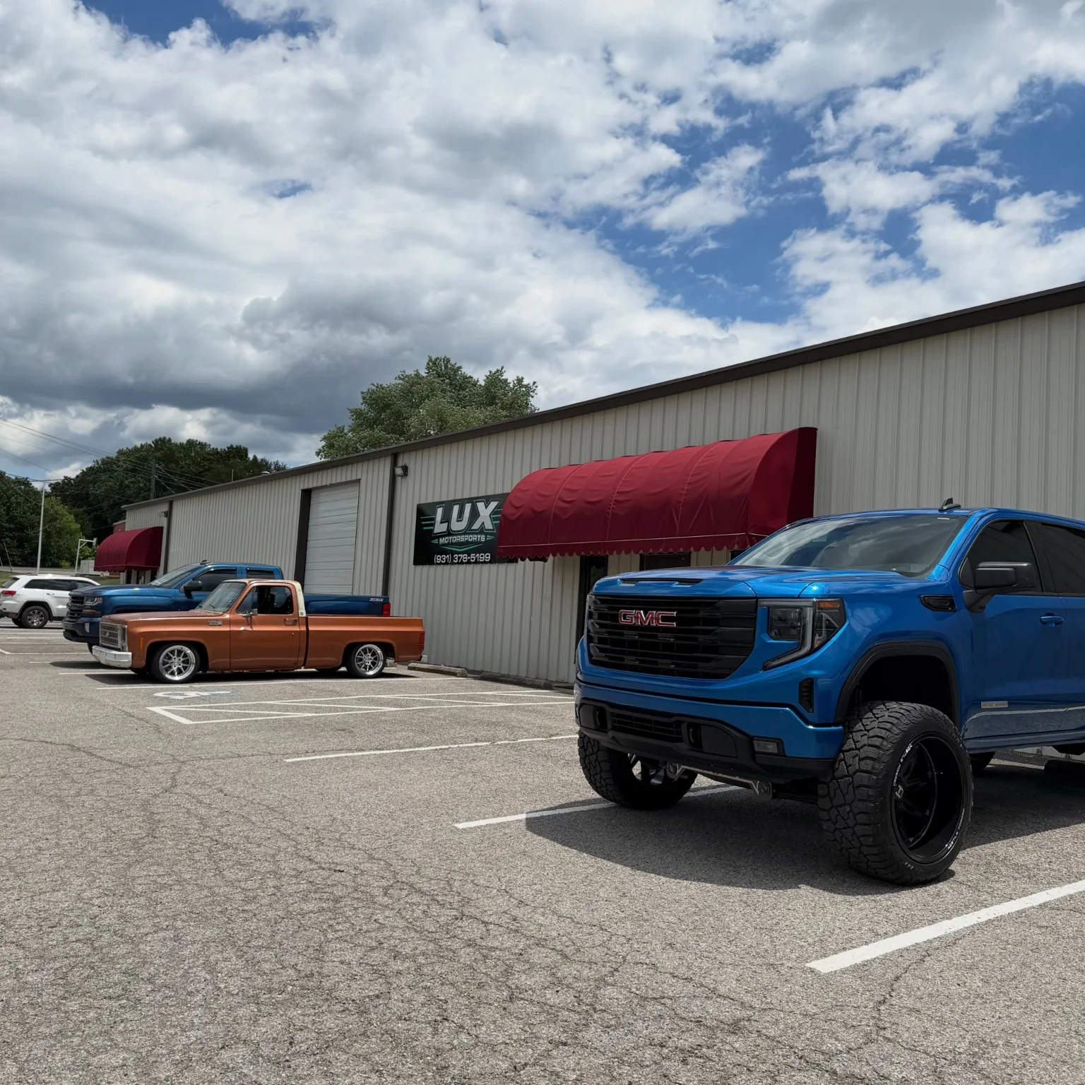 Bright blue GMC truck outside LUX Motorsports