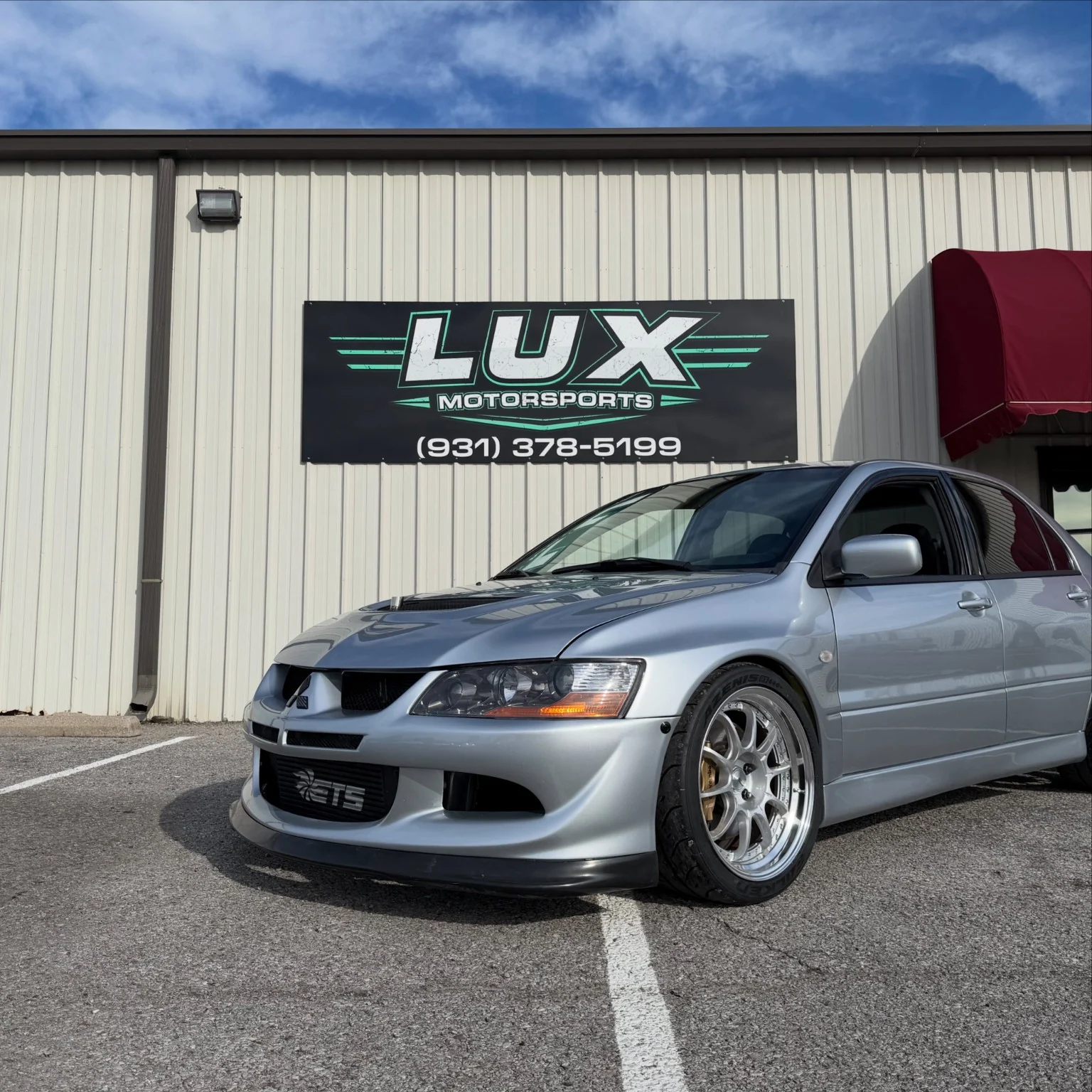 Silver Mitsubishi Evo parked outside the LUX Motorsports shop